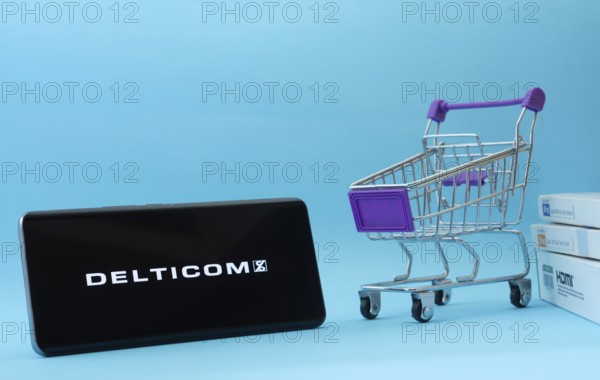 Dhaka, Bangladesh- 03 Oct 2025: Smartphone with Delticom logo next to a small shopping cart and