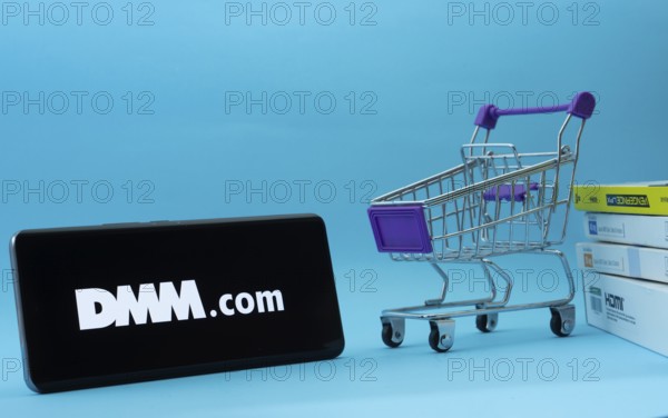 Dhaka, Bangladesh- 03 Oct 2025: Smartphone with Dmm.com logo next to a small shopping cart and