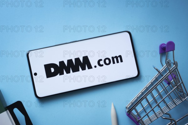 Dhaka, Bangladesh- 03 Oct 2025: Smartphone displaying Dmm.com logo with shopping cart on a blue
