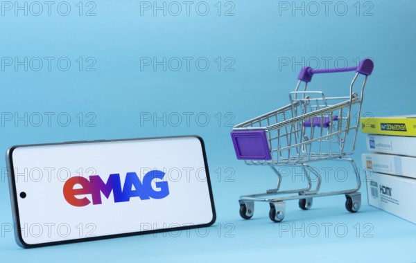 Dhaka, Bangladesh- 03 Oct 2025: Smartphone with Emag logo next to a small shopping cart and boxes