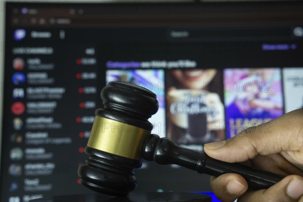 Dhaka, Bangladesh- 30 Sep 2025: A hand holds a gavel in front of a computer screen displaying