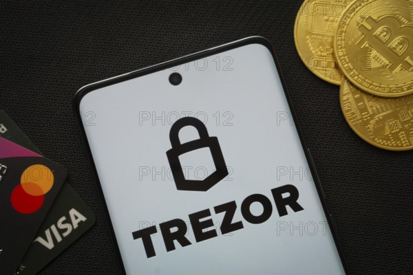 Dhaka, Bangladesh- 30 Sep 2025: Smartphone displaying Trezor logo surrounded by Bitcoin coins and