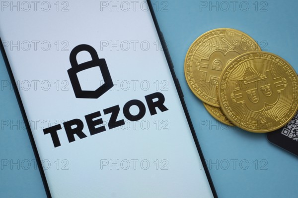 Dhaka, Bangladesh- 30 Sep 2025: Trezor logo on smartphone screen near Bitcoin coin and QR code on