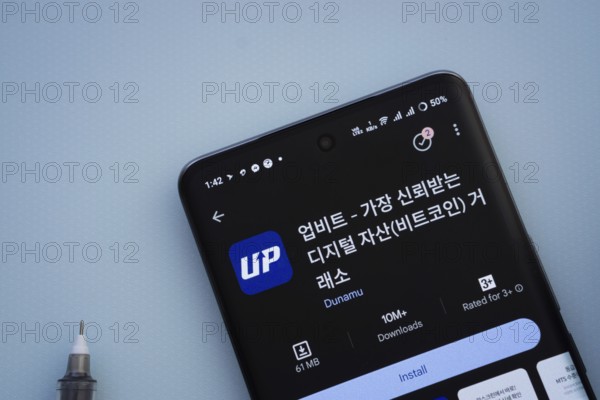 Dhaka, Bangladesh- 29 May 2025: On a blue surface, a smartphone displays the Upbit app within the