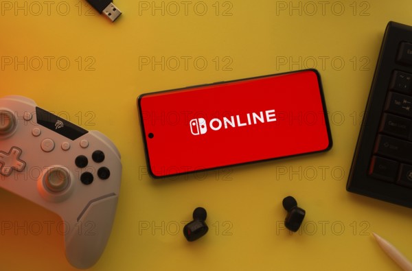 Dhaka, Bangladesh- 15 July 2025: Smartphone with nintendo online logo, game controller, and earbuds