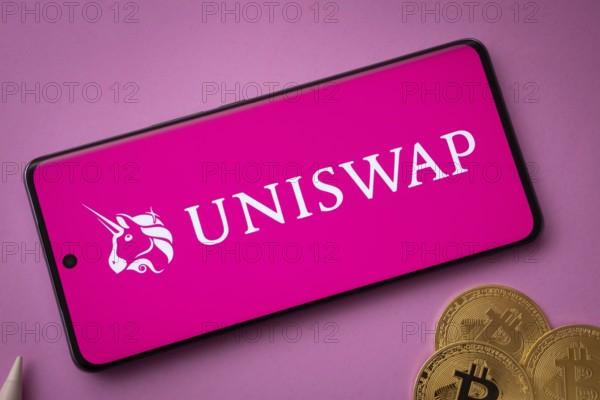 Dhaka, Bangladesh- 15 June 2025: Uniswap logo on smartphone screen near Bitcoin coin and QR code on