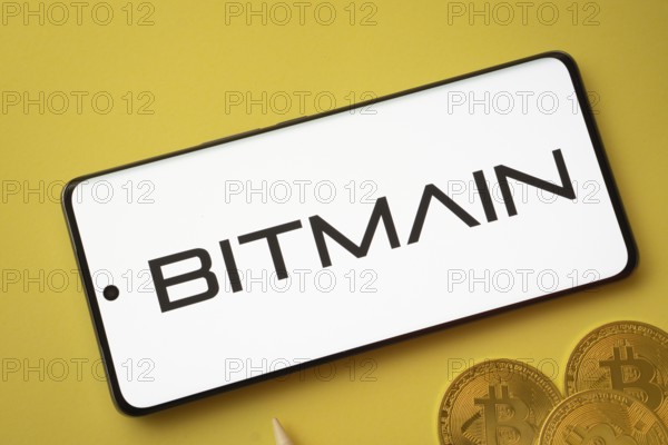 Dhaka, Bangladesh- 15 June 2025: Bitmain logo on smartphone screen near Bitcoin coin and QR code on