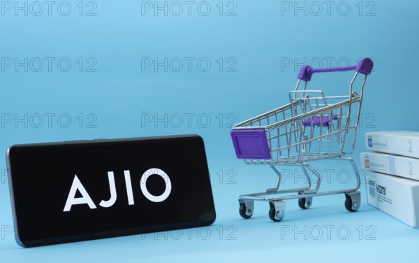 Dhaka, Bangladesh- 03 July 2025: Smartphone with AJIO logo next to a small shopping cart and boxes