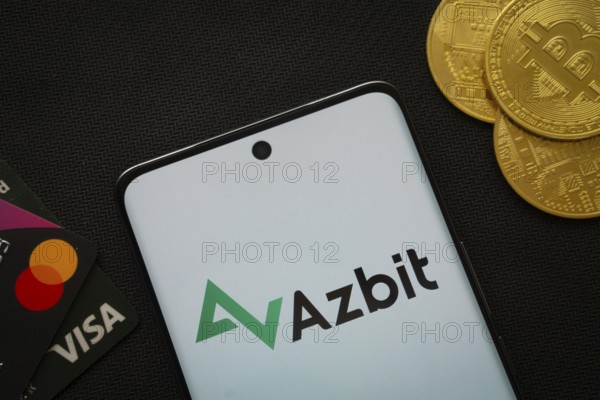 Dhaka, Bangladesh- 02 June 2025: Smartphone displaying Azbit logo surrounded by Bitcoin coins and