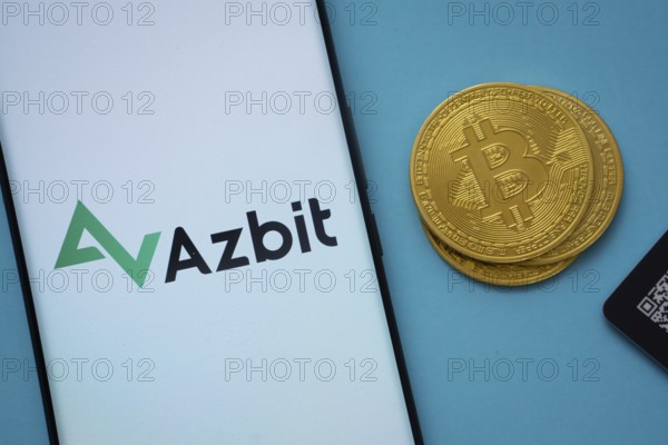Dhaka, Bangladesh- 02 June 2025: Azbit logo on smartphone screen near Bitcoin coin and QR code on