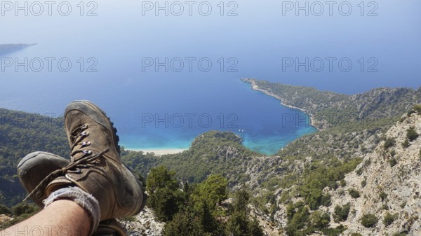 A person relaxes while hiking on a steep cliff in the mountains with spectacular views of hiking