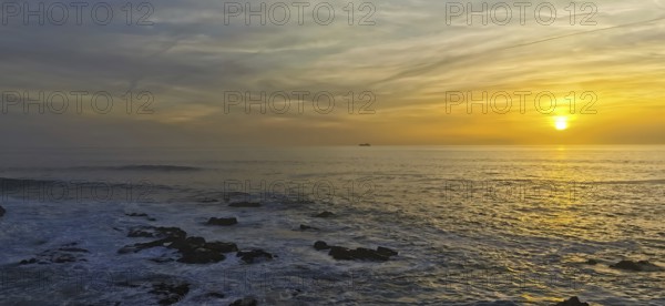 Colourful sunset over the calm sea with a ship on the horizon, hiking the Fisherman's Trail, Rota