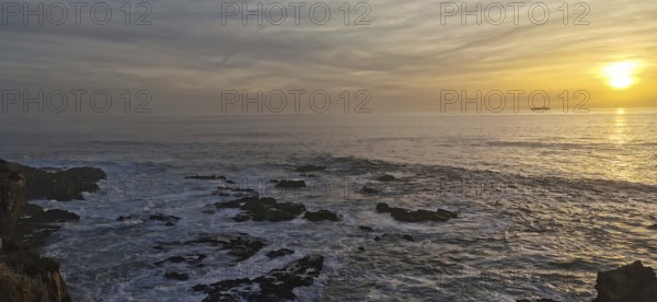 The picture shows a sunset over the sea with rocks in the foreground, hiking on the Fisherman's
