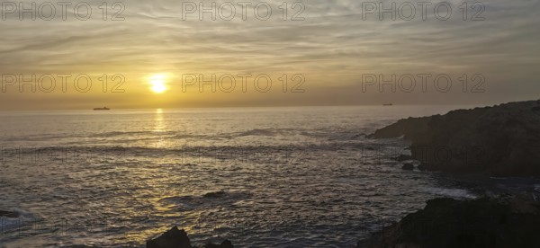 Calm sunset over the sea with two ships on the horizon, hiking the Fisherman's trail, Rota