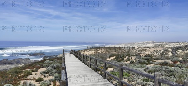 A wooden footbridge leads through vegetation along the coast, hiking on the Fisherman's Trail,
