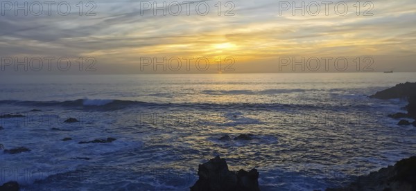 Sunset over a peaceful ocean with rocks in the foreground, hiking the Fisherman's trail, Rota