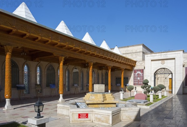 Traditional courtyard with fountain and decorated wooden pillars under clear skies, Istiklal Harbi