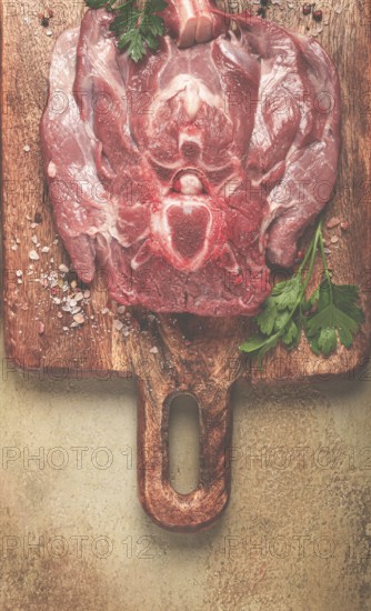 Raw steak, veal neck on the bone, fresh meat, on a cutting board, with spices, top view, without