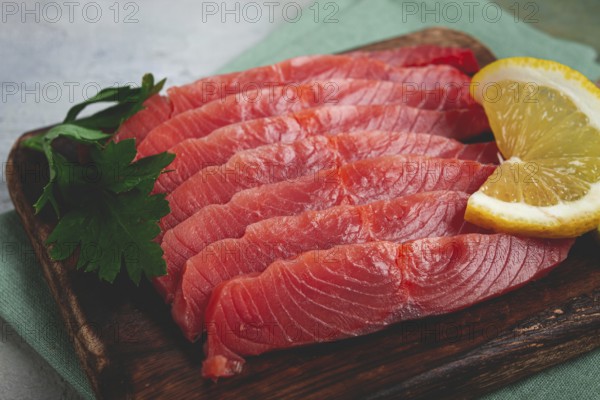 Chum salmon, cold smoked, sliced, on a cutting board, with lemon and parsley, top view, close-up,