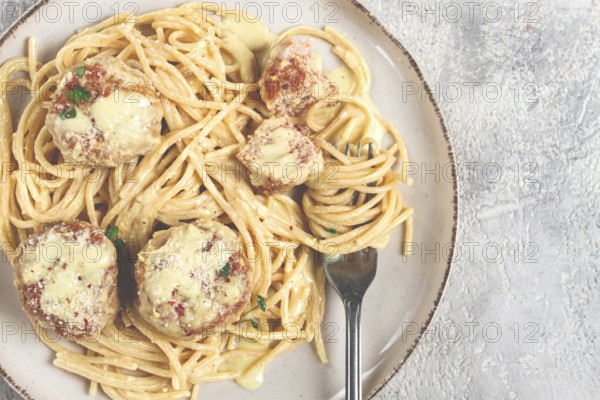 Spaghetti with chicken meatballs, with cream sauce, and parmesan cheese, and decorated with