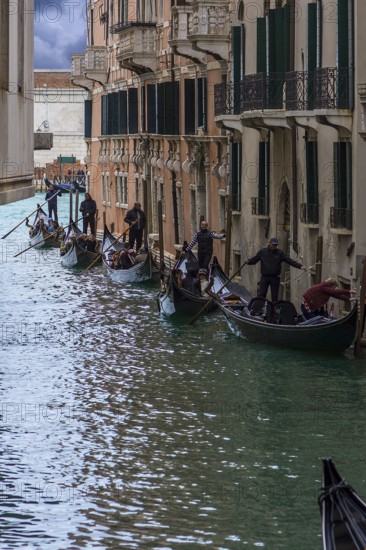 Many gondolas line up with tourists on tour through the canals of the old town, Venice, Veneto,
