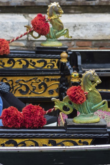 Mythological brass horse figures and red pompoms decorate the gondola, Venice, Veneto, Italy
