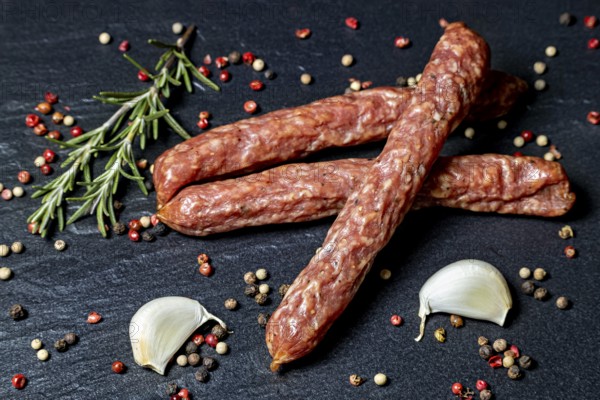 Rustic composition with salami, rosemary, peppercorns and garlic cloves, crunchy Pfefferbeiser