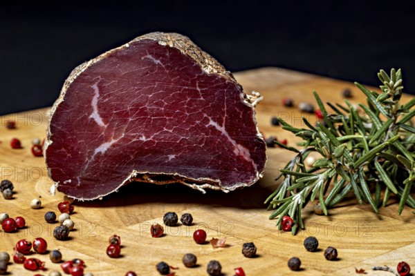 Delicious piece of raw sausage on wooden board decorated with peppercorns, delicacy ham fresh from