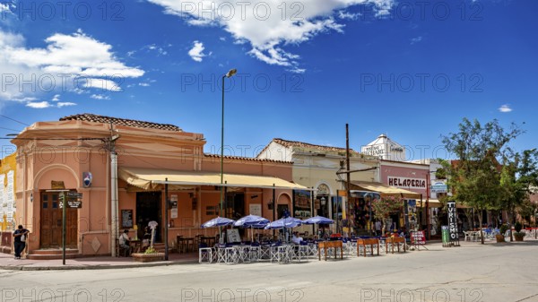Urban street scene with restaurants and outdoor seating under a clear blue sky, Downtown Cafayate,