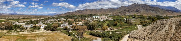 Panorama of a green village nestled in hilly and mountainous landscape, roads through the Quebrada