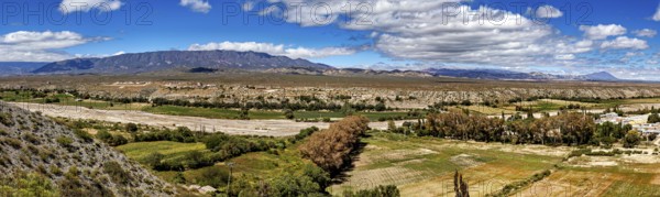 Panoramic view of green valleys and distant mountains under a cloudy sky, roads through the