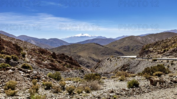 Winding road through a mountainous and dry landscape under blue sky, roads through the Quebrada de