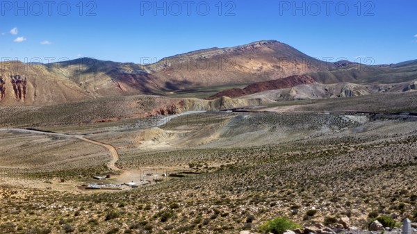 View of barren desert landscape with hills and mountains under clear skies, roads through the