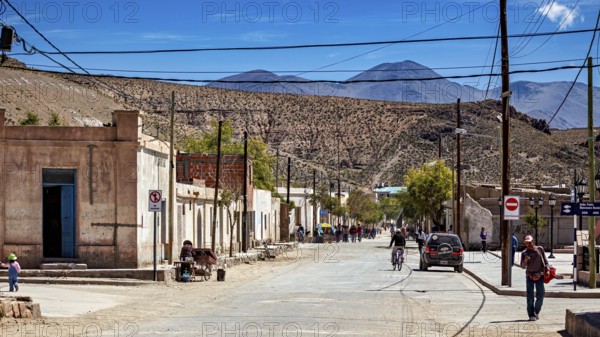 People and vehicles in a small desert town surrounded by rugged hills, San Antonio de los Cobres,