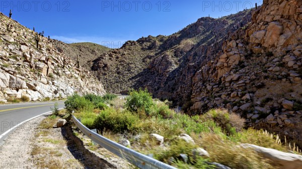 Road winds through rocky gorge in a sunny desert landscape, roads through the Quebrada de Cafayate
