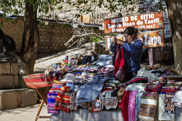 A market stand with colorful blankets and textiles in a sunny village environment in the Andes,