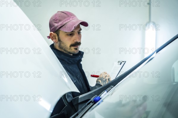 Auto repair shop worker checking a new vehicle, performing a meticulous inspection of the car body