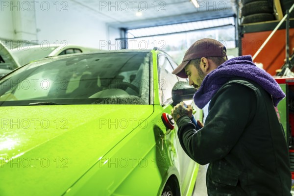 Auto body technician working on a vibrant green car, using a polisher to refine and enhance the