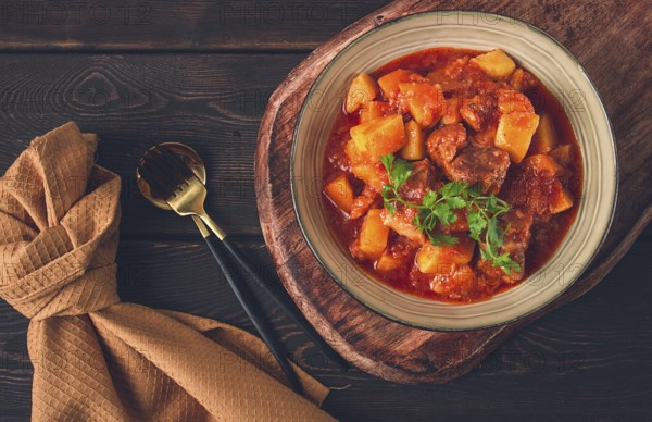 Stew with potatoes, in tomato sauce, with spices and herbs, close-up, no people, on a black