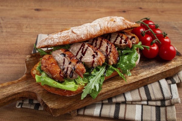 Sandwich with duck breast and arugula, balsamic sauce, on a wooden chopping board, breakfast,