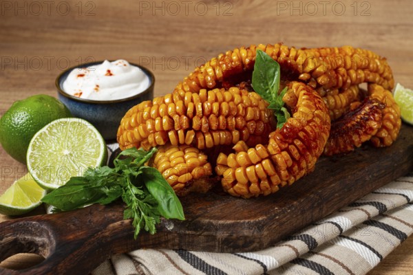 Corn ribs, with cream sauce, spices and lime, appetizer, on a wooden cutting board, homemade, no