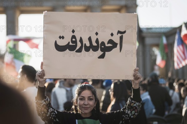 A woman holds up a sign with the inscription The Mullah Went during the demonstration by exiled