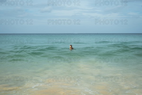 A young woman enjoys a swim in the clear turquoise waters of a tranquil beach in vacation, creating