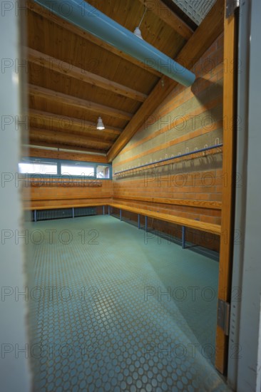 View through an open door into a changing room with brick walls and wooden ceiling, Schlehengäu