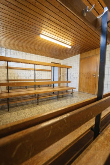An empty changing room with wooden benches and simple lighting, Schlehengäu Grund Schule Gechingen,