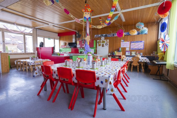 Bright kindergarten room with colorful decorations and red furniture creates a festive atmosphere,