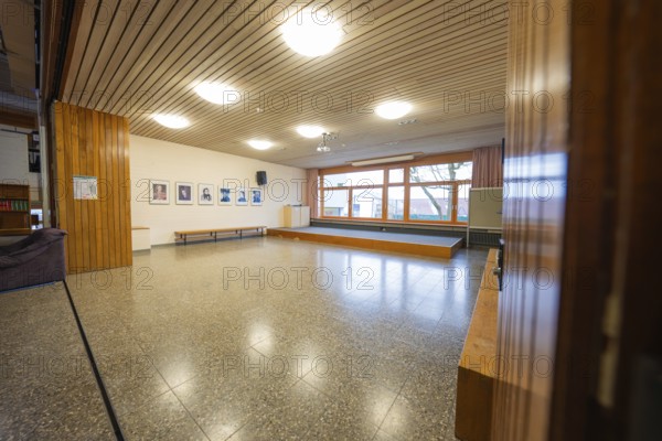 Another common room with parquet floors, wooden walls and large windows, decorated with picture