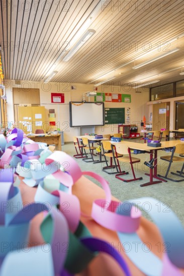 Classroom with colorful paper chains and blackboards, equipped with wooden school desks,