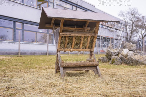 Wood hay rack on a hay covered meadow next to stones, Schlehengäu Grund Schule Gechingen, Calw