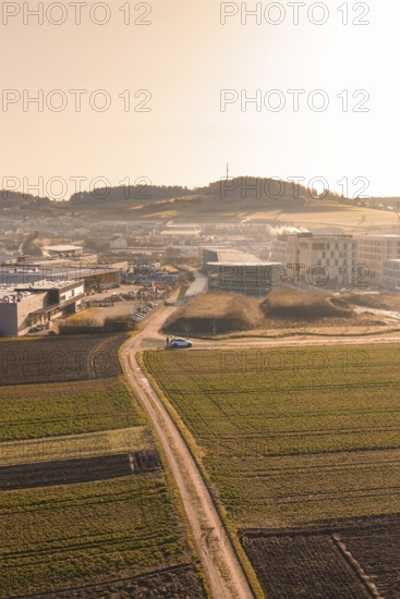 Rural road leads to large buildings in morning light over fields, new hospital at Calw health
